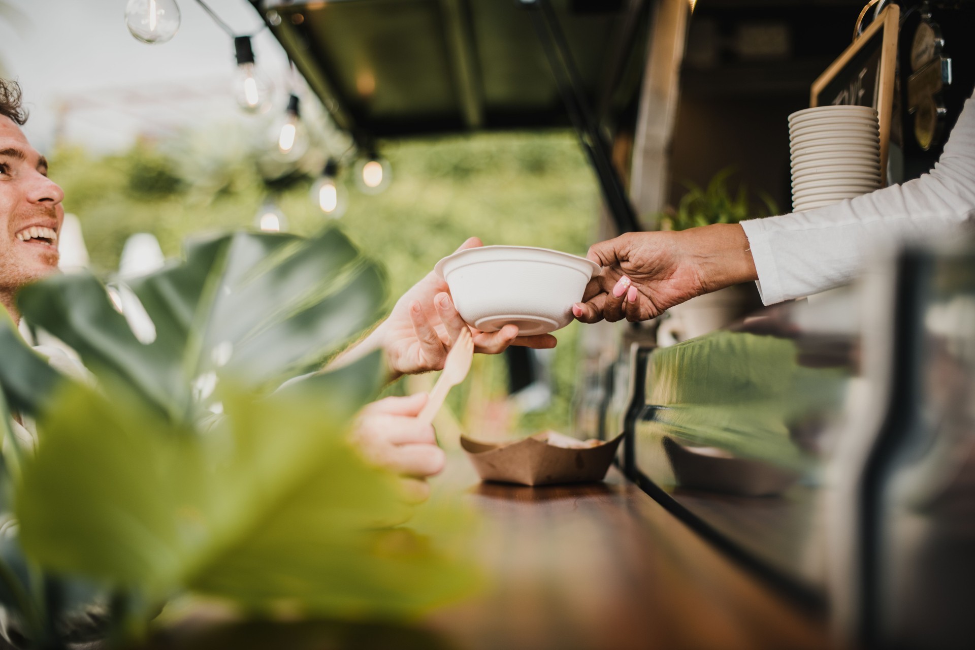 Young man buying take away food from food truck - Focus on food plate